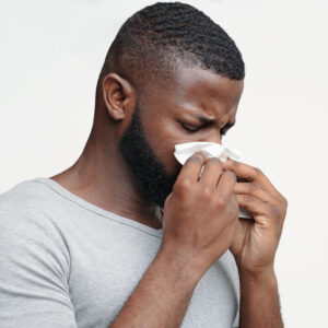 Man holding nose with tissue